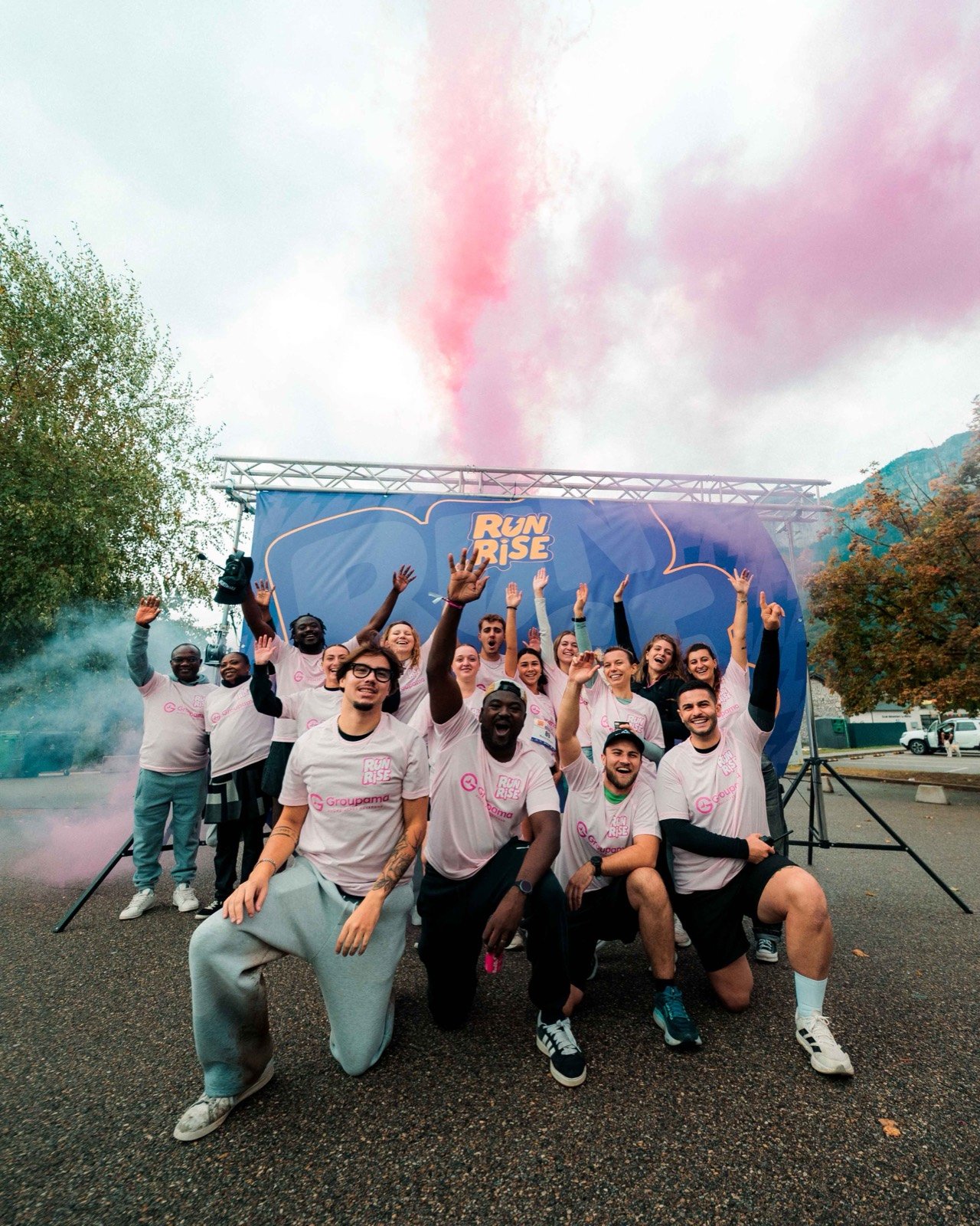 L'équipe d'organisation de RunRise pose devant l'arche avec un fumigène rose