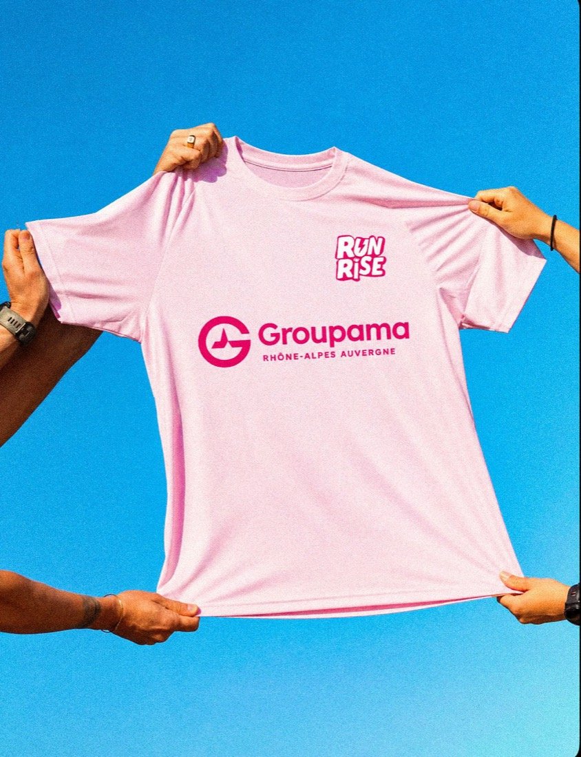 Maillot rose RunRise tendu à bout de bras devant un ciel bleu
