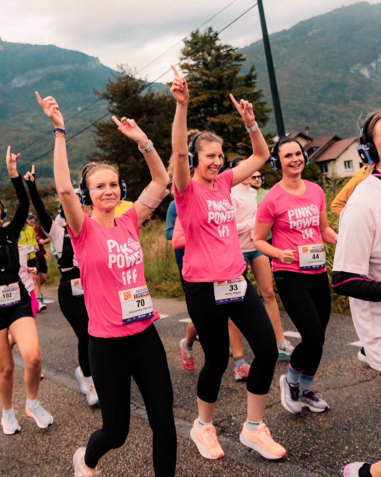 Des participantes en t-shirt rose lèvent les bras en courant avec leur casque
